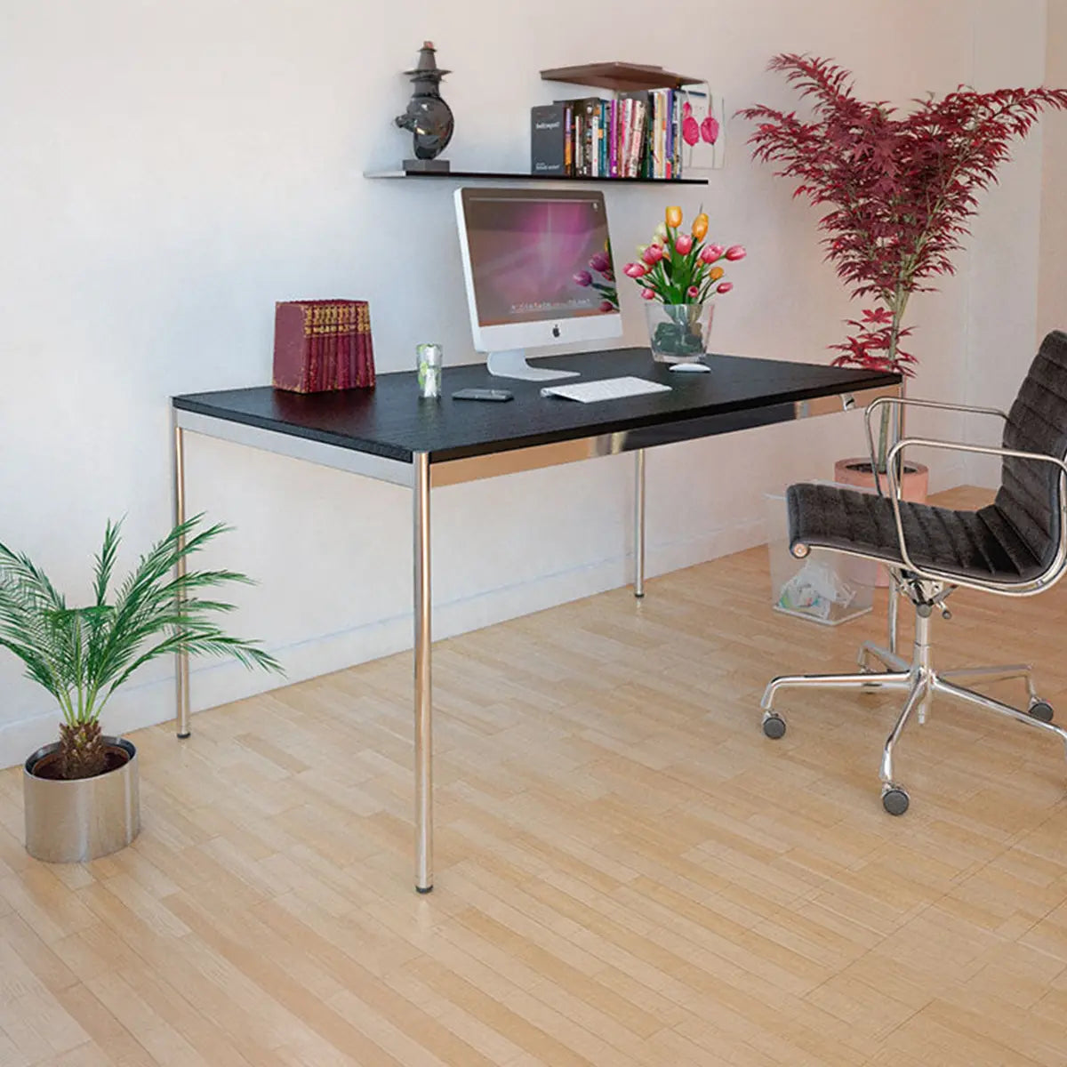 USM Haller Tisch in Schwarz im Homeoffice, seitliche Ansicht mit Buerostuhl, Pflanze und Dekoration auf Holzfussboden