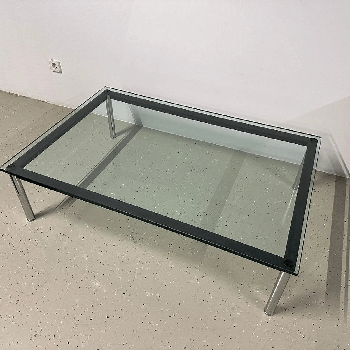 Cassina LC10-P Couchtisch, rechteckige Glasplatte mit schwarzem Rahmen und verchromten Rundbeinen, Schrägansicht von oben.