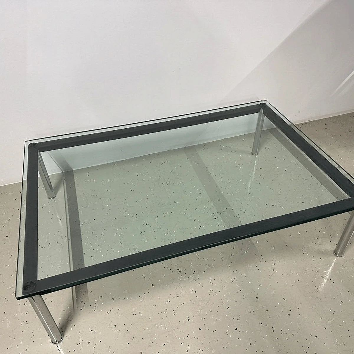 Cassina LC10-P Glastisch mit schwarzem Rahmeneinsatz und verchromten Beinen, Perspektive leicht von oben.