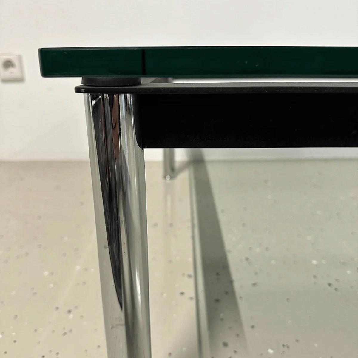 Detail des verchromten Tischbeins und der starken Glasplatte mit schwarzem Rahmeneinsatz am Cassina LC10-P.