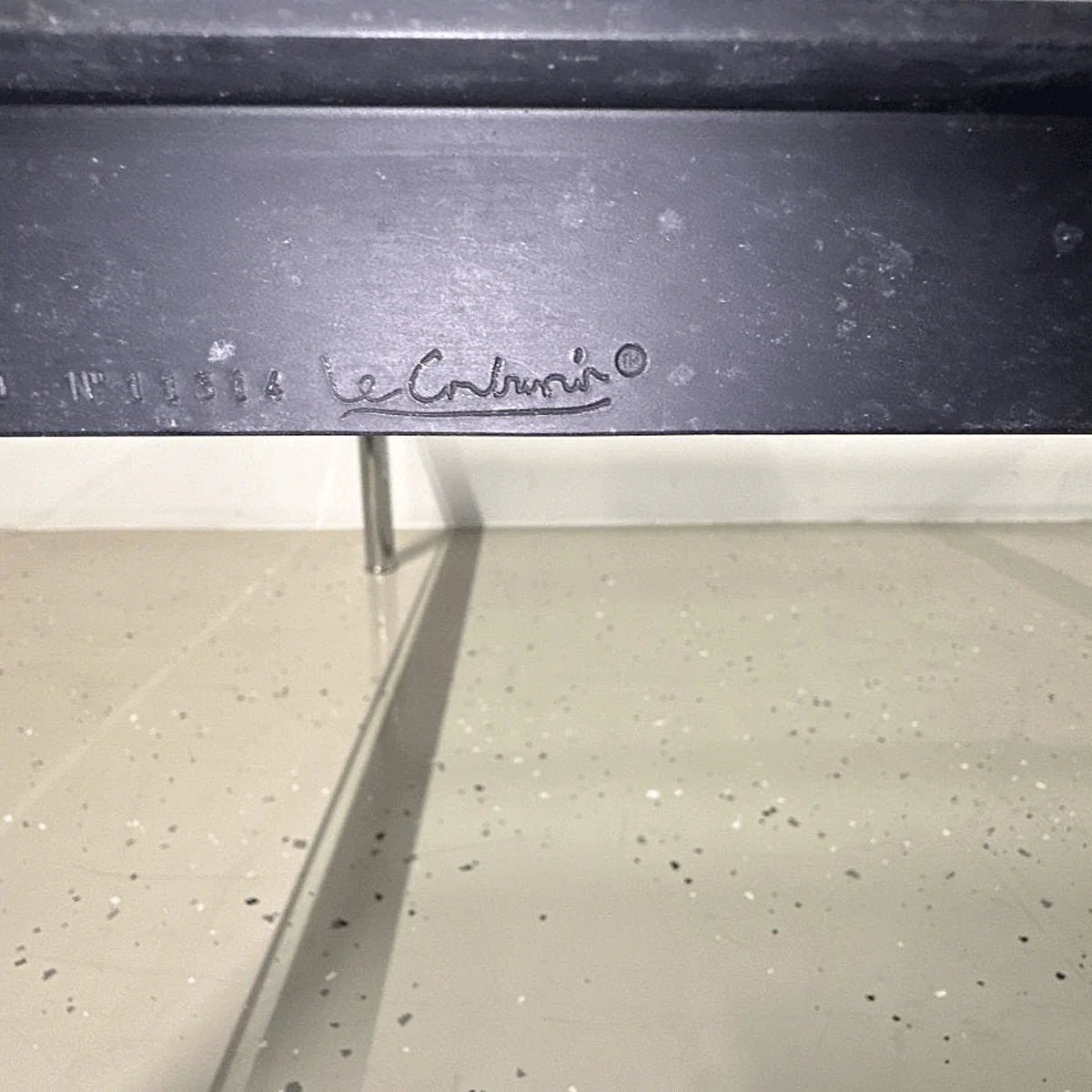 Geprägte Le-Corbusier-Signatur am schwarzen Rahmen des Cassina LC10-P Tisches, Nahaufnahme.