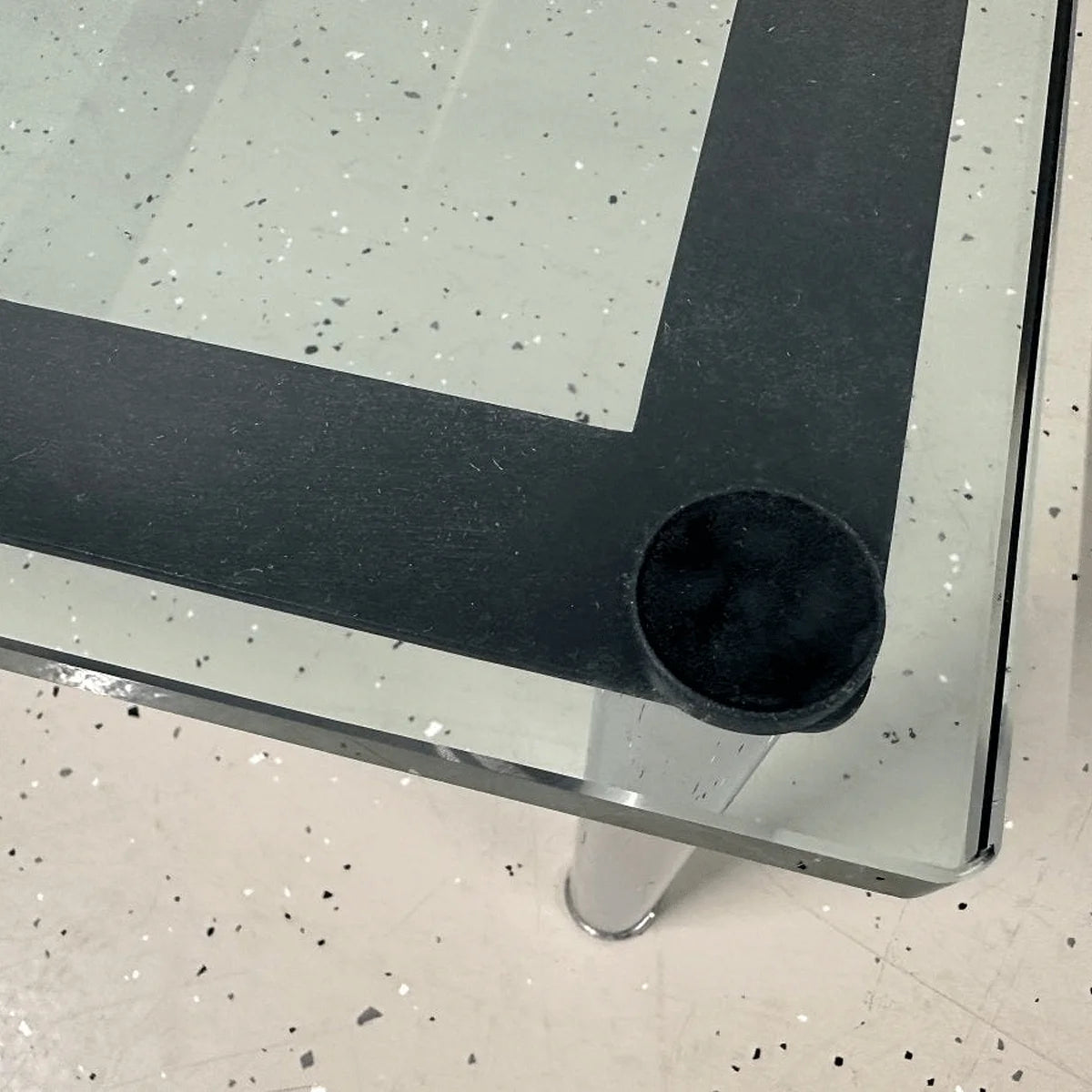 Ecke des Cassina LC10-P: Glasauflage mit runder Auflagefläche und schwarzem Rahmen, Detailaufnahme.