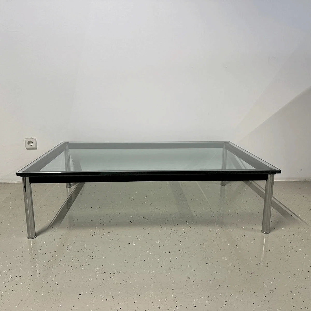 Cassina LC10-P Couchtisch frontal: rechteckige Glasplatte, schwarzer Rahmen und vier verchromte Rundbeine