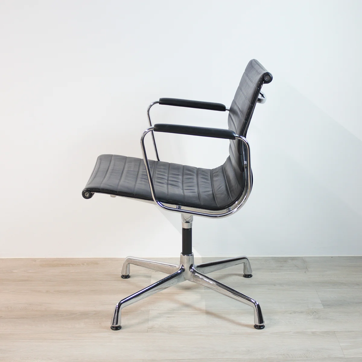 Vitra Alu-Chair EA 108 Leder, schwarz seitliche Aufnahme Büro auf Parkettboden