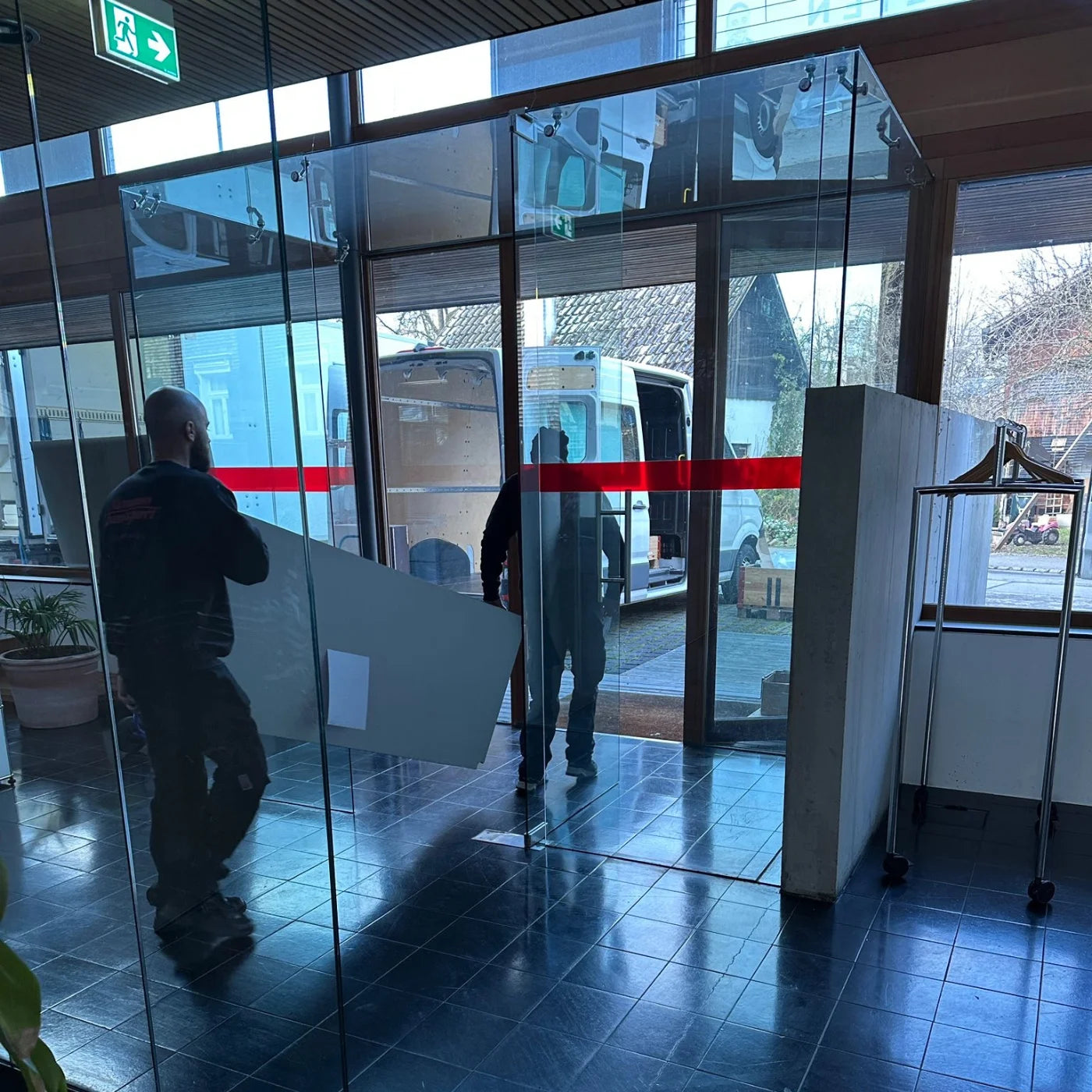 Monteure vom USM Markt transportieren USM Haller Möbelstücke aus dem Gebäude in einen weißen Lieferwagen