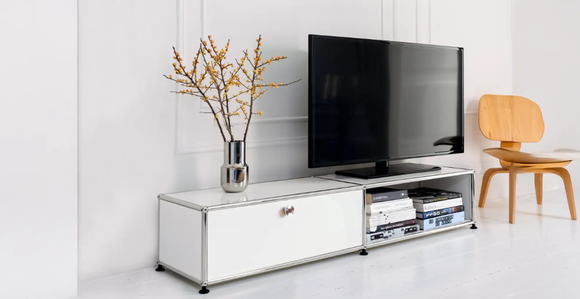 Weisses USM Haller Lowboard als TV-Board mit Fernseher, Vase und Buechern in hellem Wohnraum