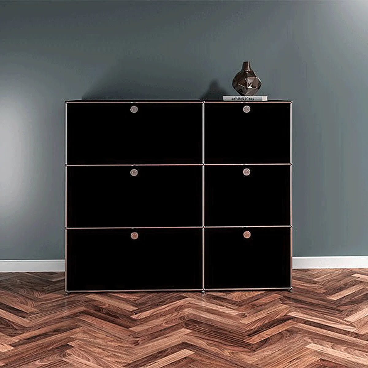 USM Haller Sideboard in Schwarz mit sechs Klapptueren vor dunkler Wand, ruhige Front