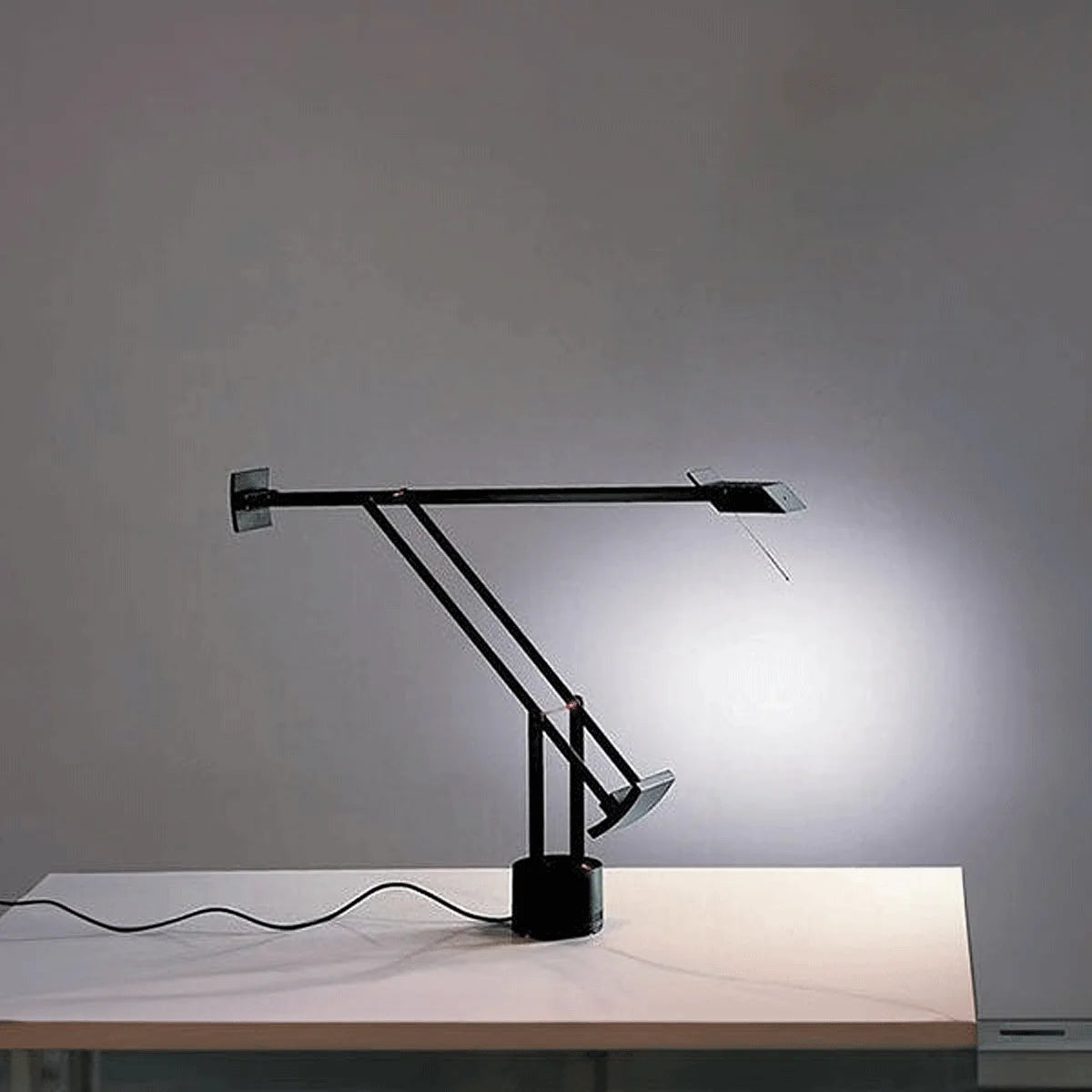 Artemide Tizio Tischleuchte in Schwarz mit roten Gelenkpunkten, seitliche Ansicht im Ambiente.