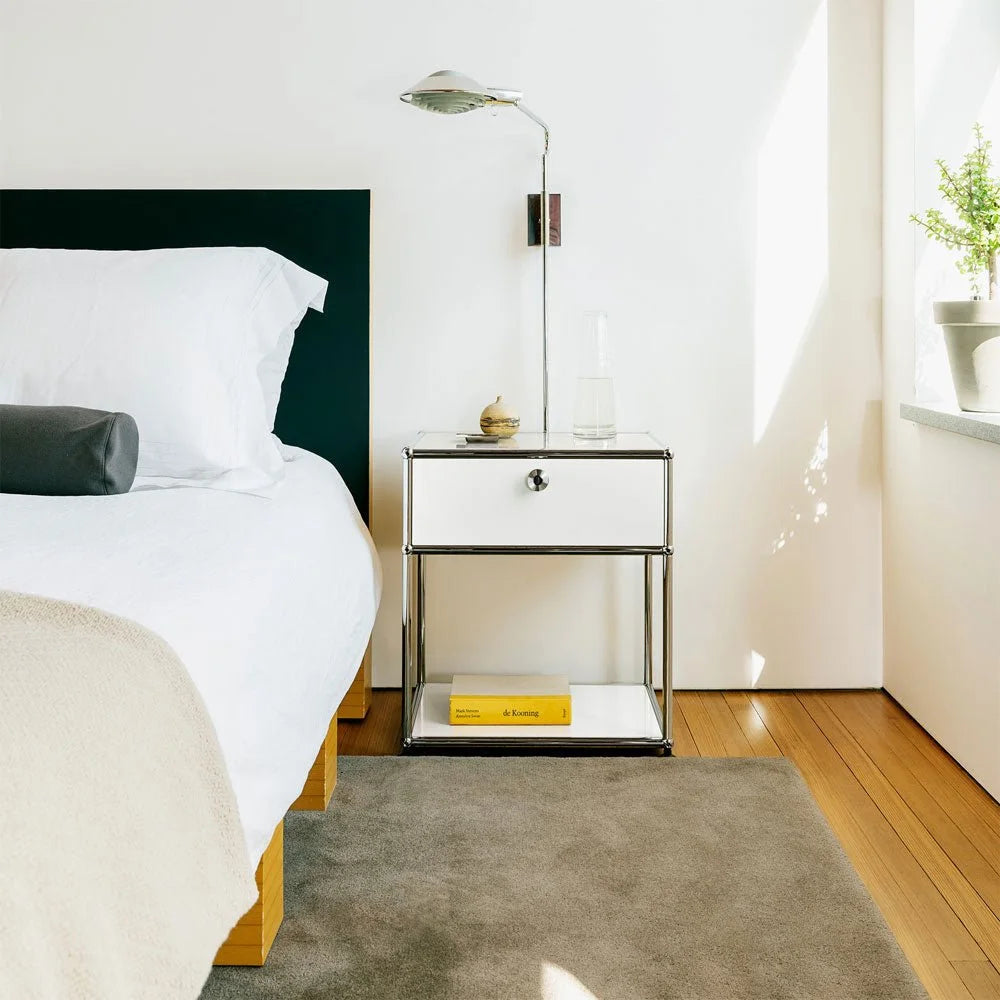 USM Haller Nachttisch am Bett mit Klapptür und verchromtem Rahmen – stilvolle Ablage im modernen Schlafzimmer