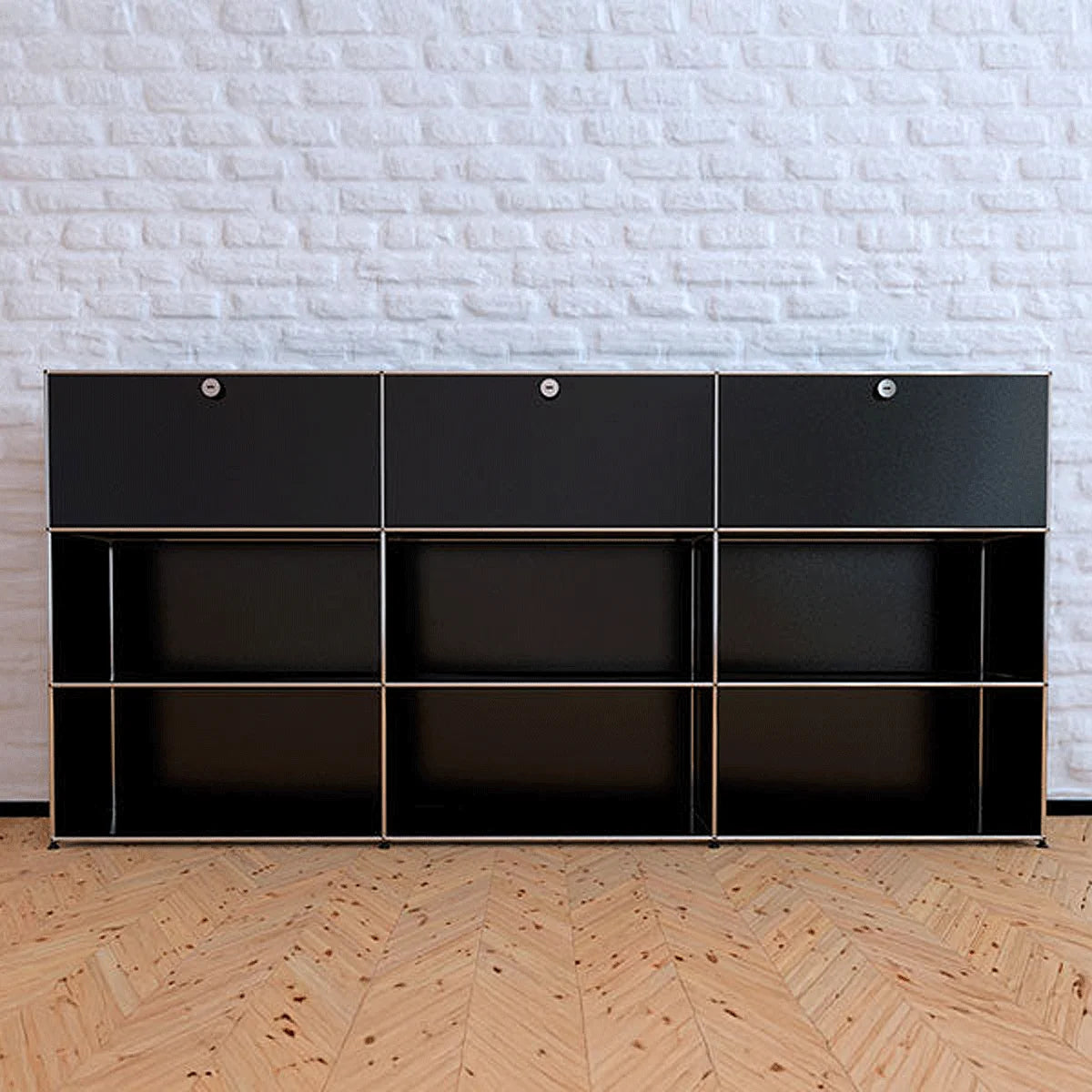 USM Haller Highboard schwarz vor einer weißen Mauerwand mit Parkettboden