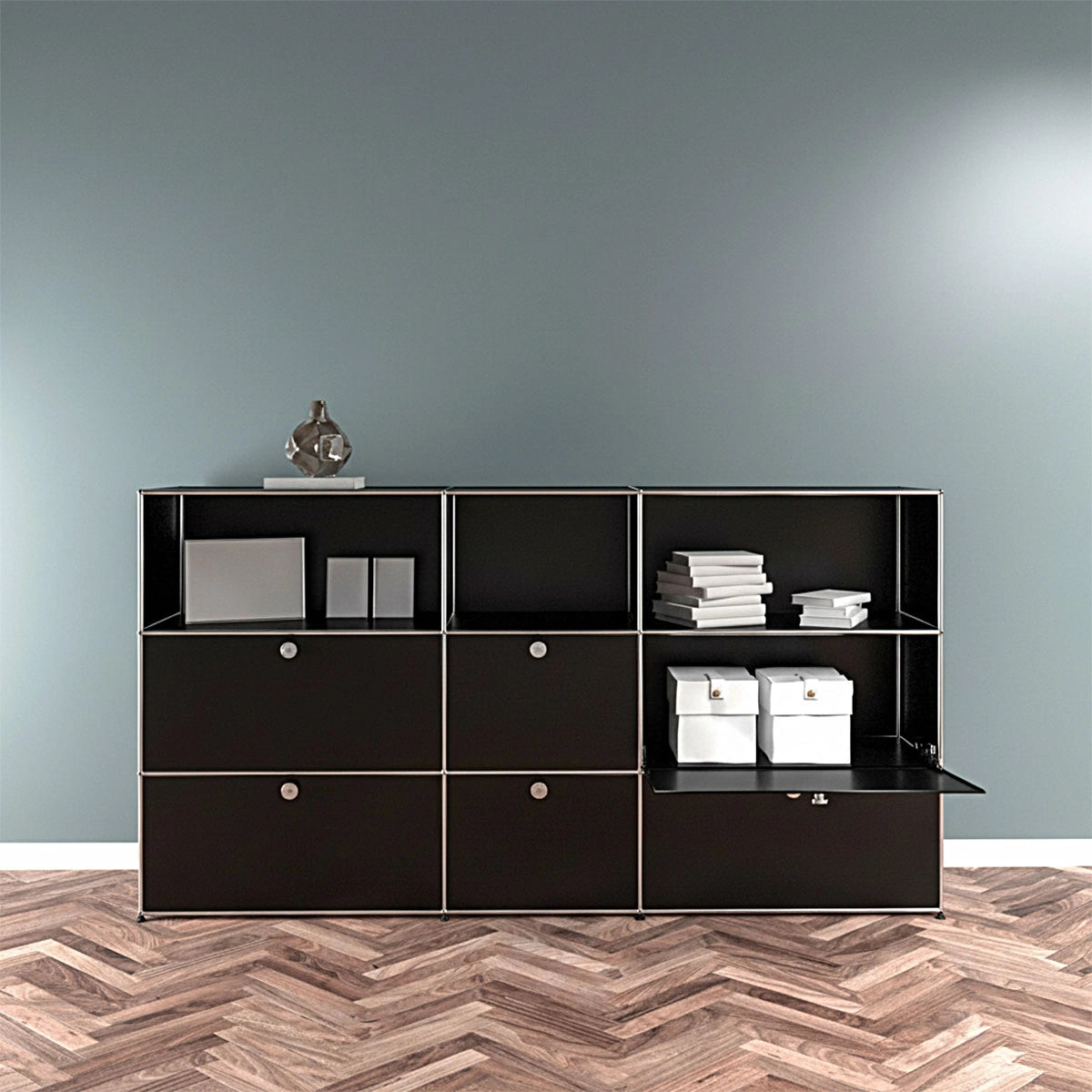 USM Haller Highboard 3x3 in Schwarz – Front, geöffnete Klapptür zeigt Stauraum für Ordner und Boxen